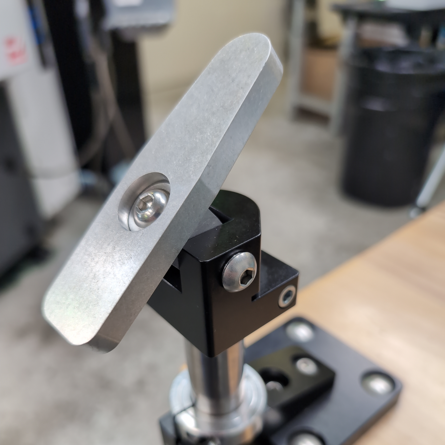 Metal clamp or holder attached to a wooden surface with a blurred background