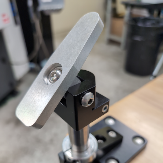Metal clamp or holder attached to a wooden surface with a blurred background